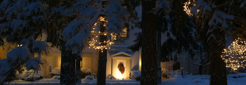 night time, trees and against a snowy backdrop, Geneva on the Lake in the background with holiday lights.