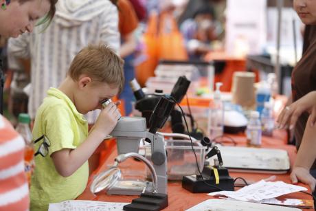Boy looks through microscope at Imagine RIT