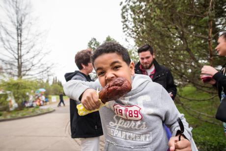 boys bites into a turkey leg at the Rochester Lilac Festival