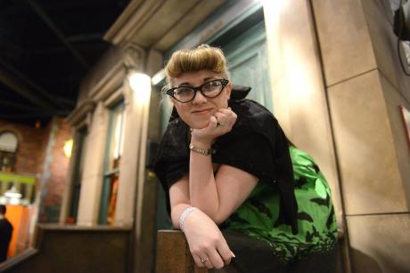 woman stands on the Sesame Street stoop at the Strong Museum