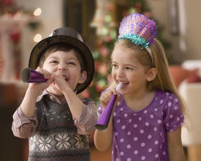 A boy and girl with noisemakers on New Year's Eve.