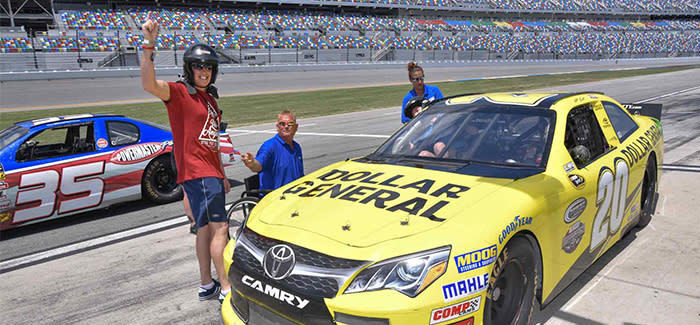 People are gathered around a stock car at Daytona International Speedway and are about to experience the NASCAR Racing Experience in Daytona Beach