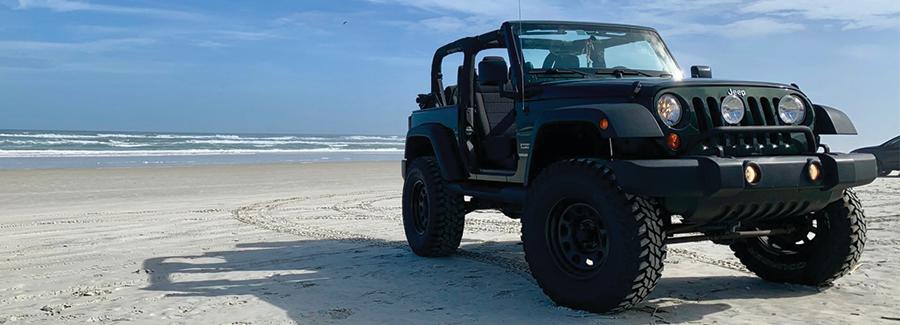 A jeep sits parked on the hard-packed white sands of Daytona Beach