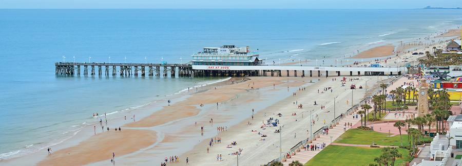 An aerial view of the wide Daytona Beach coastline and the Daytona Beach Pier and Oceanfront Bandshell