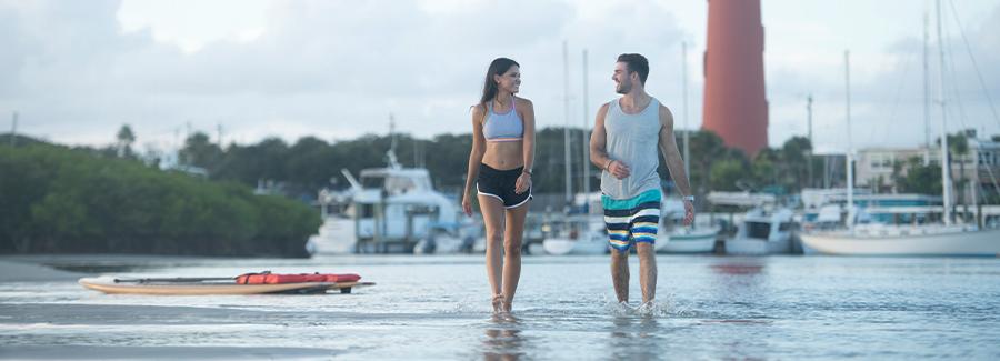 A couple strolls a sandbar after paddleboarding near Ponce Inlet Lighthouse