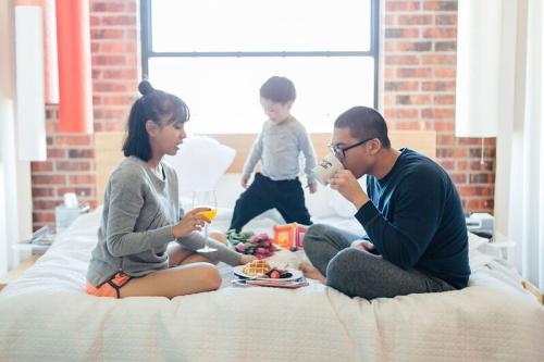 A family sits on the hotel bed during their staycation at the Nylo in Irving.
