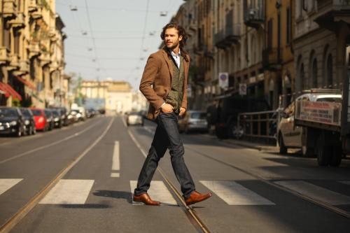 A man walking across a crosswalk in stylish clothing
