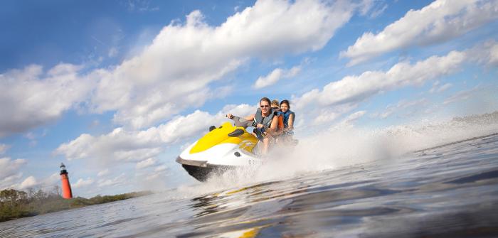 A family jet skis in Ponce Inlet with the lighthouse in the background.