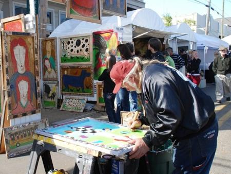 Man painting at an outdoor table set up at Three Rivers Art Festival in Covington, LA