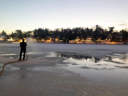 Man with hose making ice to freeze over Hiawatha Lake