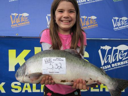 A girl holds up a pink salmon