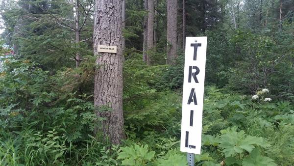 a sign in a forest marking the start of a hiking trail