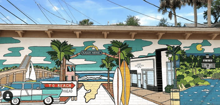 A mural in New Smyrna Beach features a classic car, the beach and surfboards