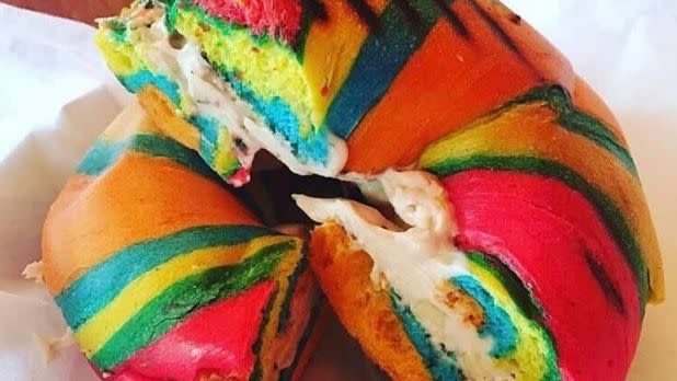 A photo of a rainbow bagel cut in half with cream cheese