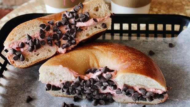 A picture of a bagel split in half with strawberry cream cheese and chocolate chips