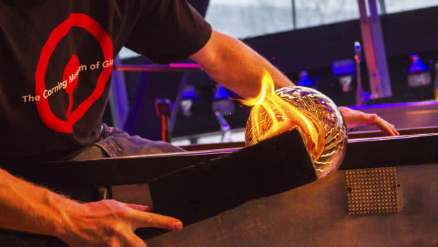 A glassblower shaping glass at the Corning Museum of Glass