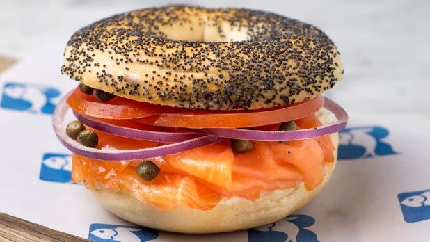 A photo of a poppy seed bagel with salmon onions and tomato on a Russ and Daughters parchment paper