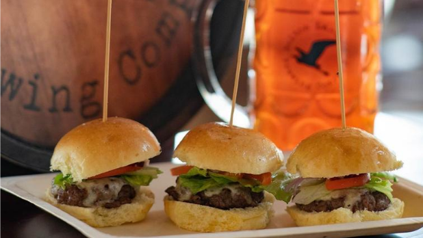 Three burger sliders and a beer in the background