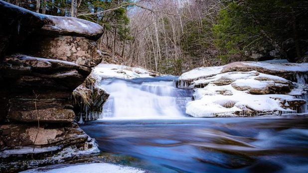 A snowy day at Kaaterskill Falls with frozen water running onto rocks and snow