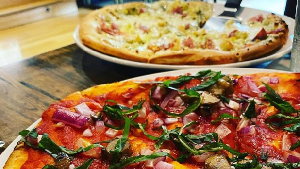 Two pizzas on a table from Dina's Restaurant