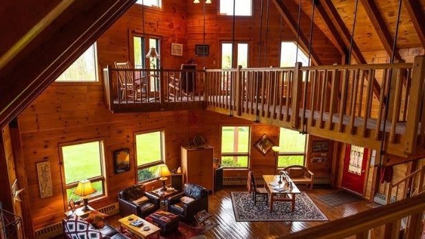Point Au Roche Lodge interior, with suspended wooden walkway above a main floor with furniture