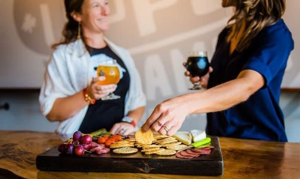 2 people reaching for cheese on board