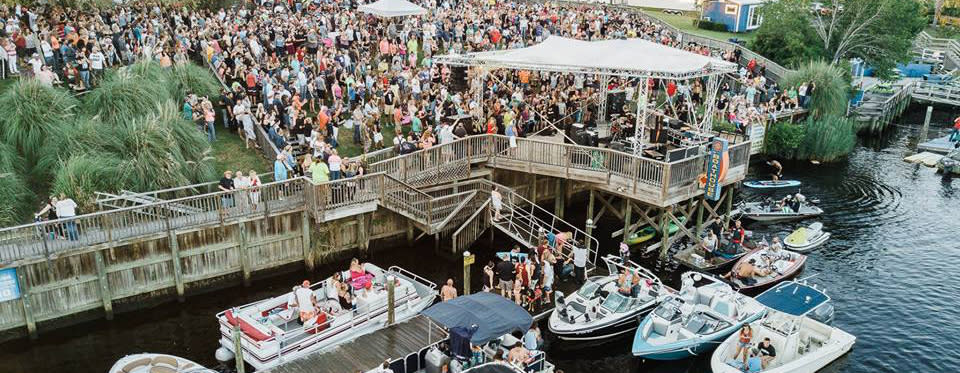 Crowds pack the waterfront to hear live music under a tent at The Landing at the Boathouse