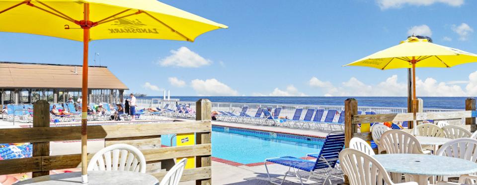 Outdoor dining tables with yellow umbrellas overlook a pool at Ocean Annie's in Myrtle Beach