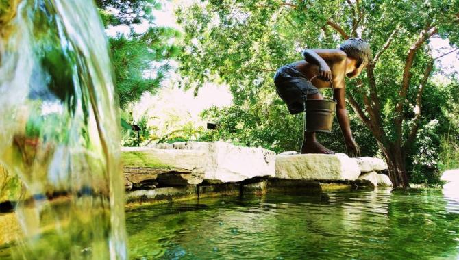 A water feature at the Garden on the Rocks with a statue of a young boy standing on the rocks with a bucket