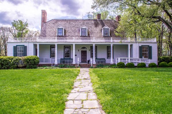 Picture of a white historic house, known as Rippon Lodge.  Walkway with grass with a house set as backdrop.