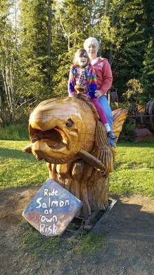 Child and grandparent on wooden salmon at the Alaska Salmon Bake