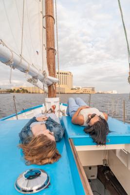 Two women laying on the deck of a boat sitting in the water.