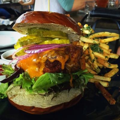 Fully-loaded burger stacked high with patties, cheese, lettuce, onion, and pickles, next to a pile of French fries from Wolf's Ridge