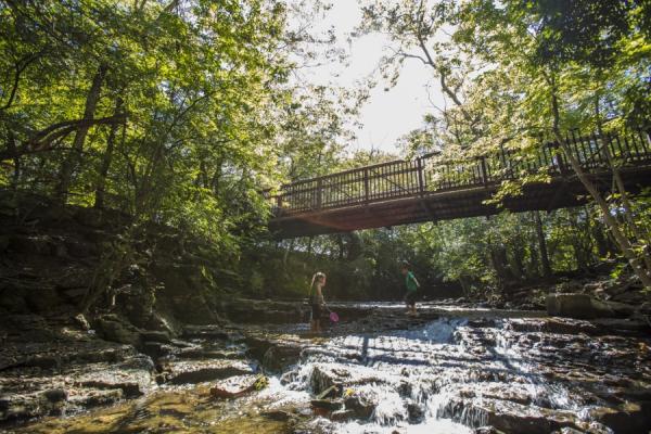 Two kids playing under a bridge in the water at Indian Run Falls.