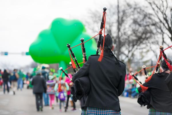 St. Patrick's Day Parade Bagpiper walking behind a giant green shamrock balloon.