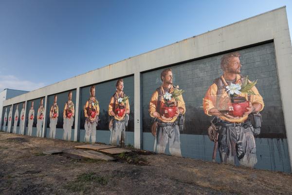 A mural at the Rail Arts District featuring the slowing changing image of a man holding a flower pot.