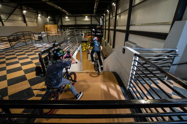 BMX biker is going down a ramp indoors