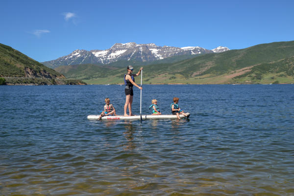 Father Stand up paddle-boarding with three kids