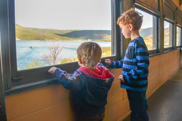 Two boys looking out at a lake from a train car window