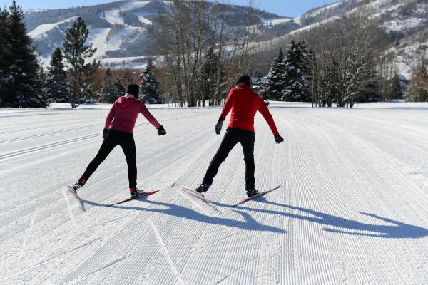 A coach and student are skate skiing on nordic skis