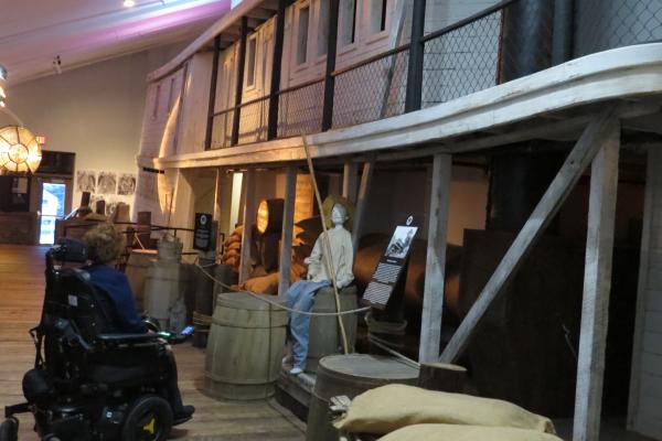 A women in a wheelchair viewing an exhibit at the Lake Pontchartrain Basin Maritime Museum