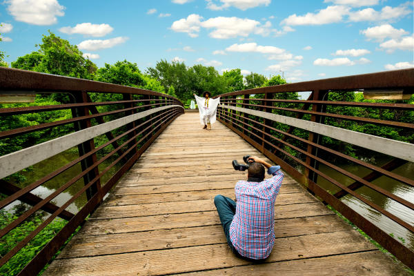 Photographer taking photo of model on the bridge leading to the water feature at Oyster Creek Park.