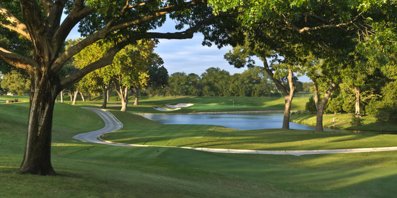 A tree-lined path on the golf course green at the Colonial Country Club in Texas