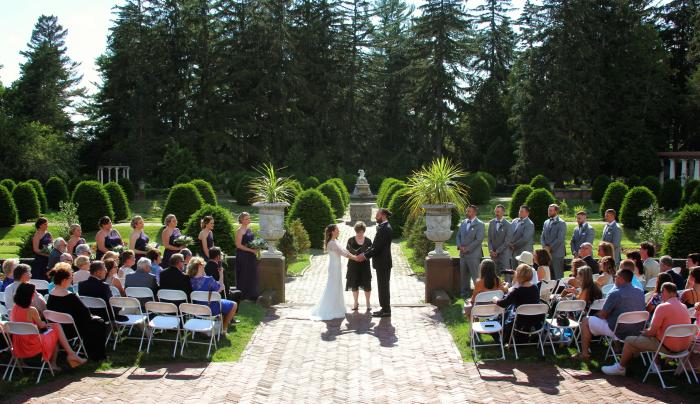 A bride and groom exchange vows during their wedding at Sonnenberg Mansion and Gardens A bride and groom exchange vows during their wedding at Sonnenberg Mansion and Gardens