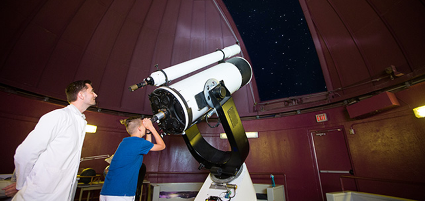 Child looking through telescope at the Observatory at the HR MacMillian Space Centre