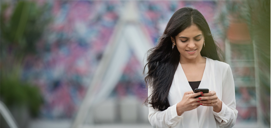 Young woman searching her cellphone and smiling.