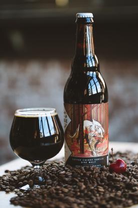 Bottle and glass of dark beer from Wolf's Ridge Brewing sitting atop pile of coffee beans