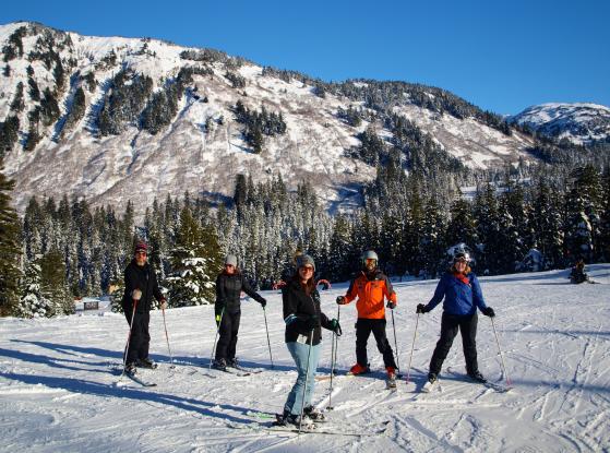 A group of friends skiing in the snow and tree covered Eaglecrest mountains in Juneau. 