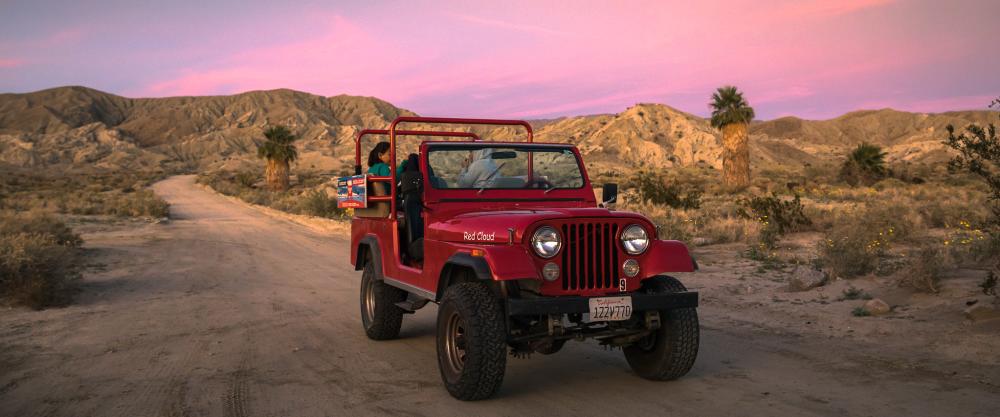 Desert Adventures Red Jeep Tour at sunset on a dirt road.