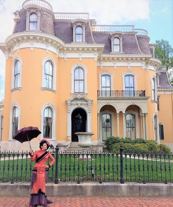 A woman in period Victorian costume outside the Culbertson Mansion State Historic Site.